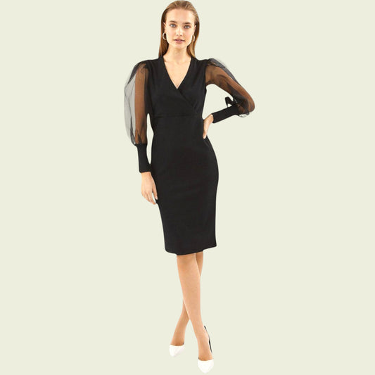 Woman wearing a black dress with sheer sleeves on a beige background