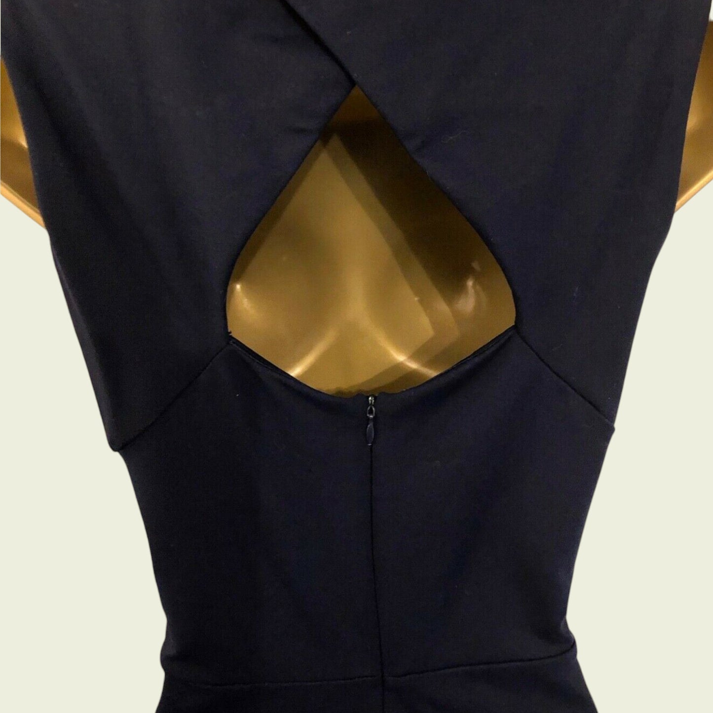 Black dress with a unique cutout design on a beige background