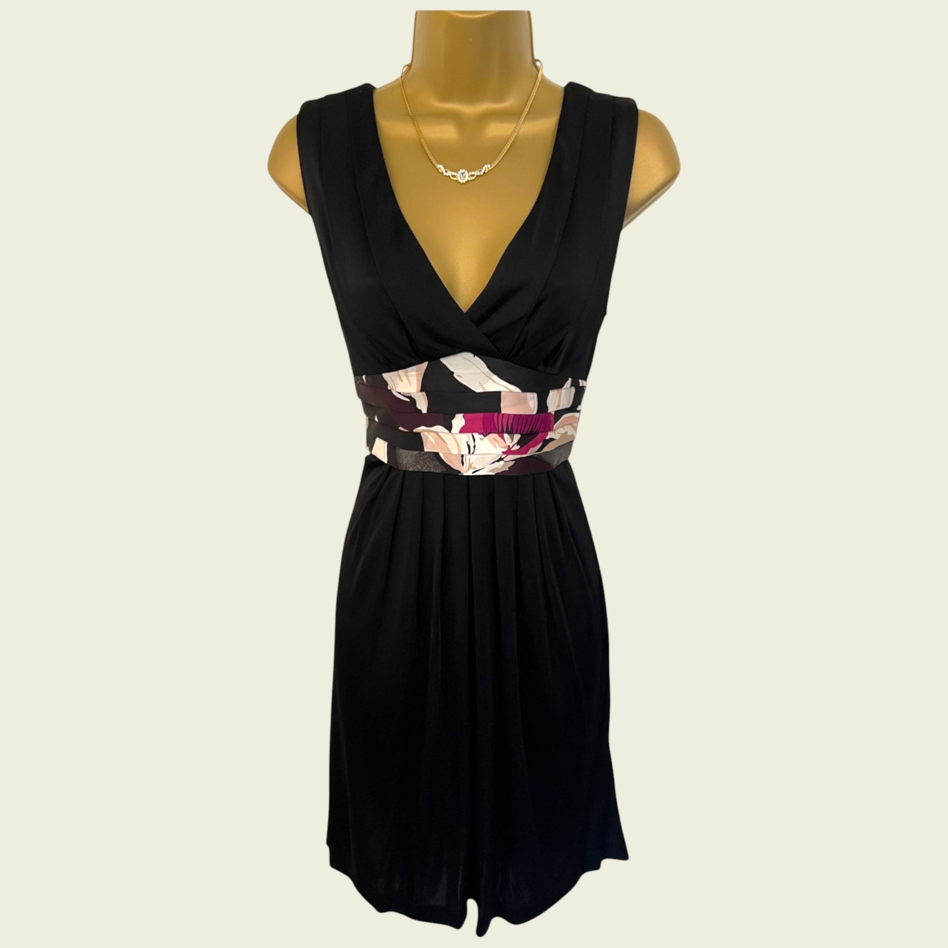 Black dress with floral belt on a mannequin against a beige background