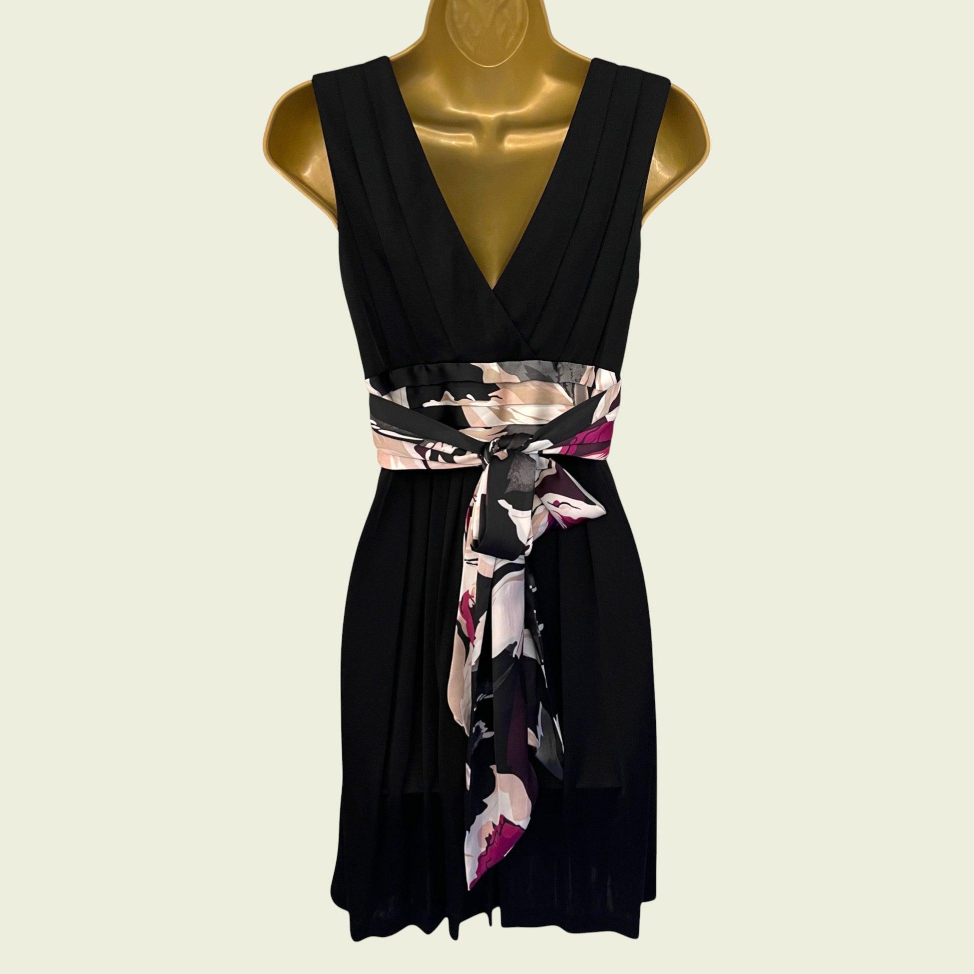 Black dress with a floral belt on a mannequin against a beige background