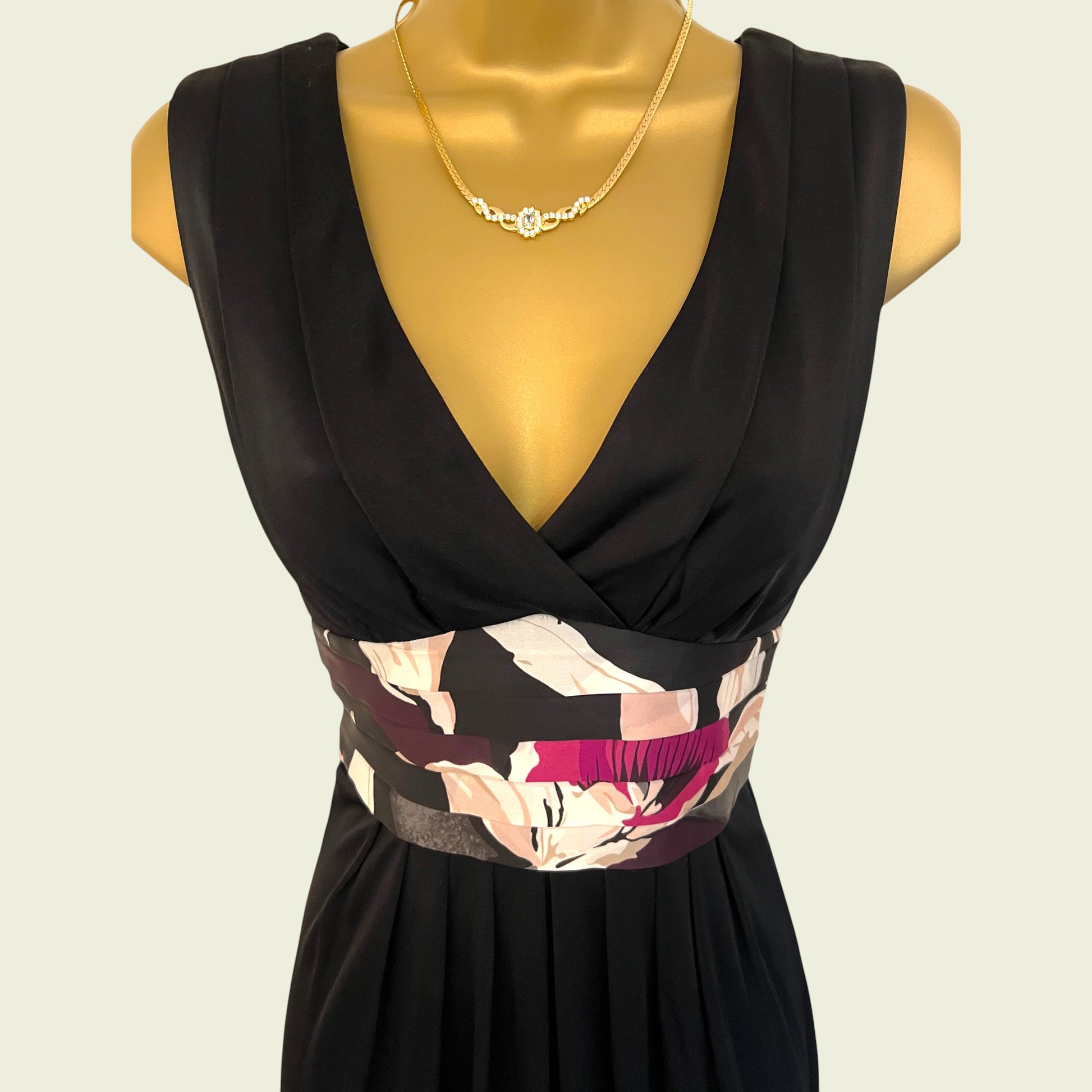Black dress with floral patterned belt on a mannequin against a beige background