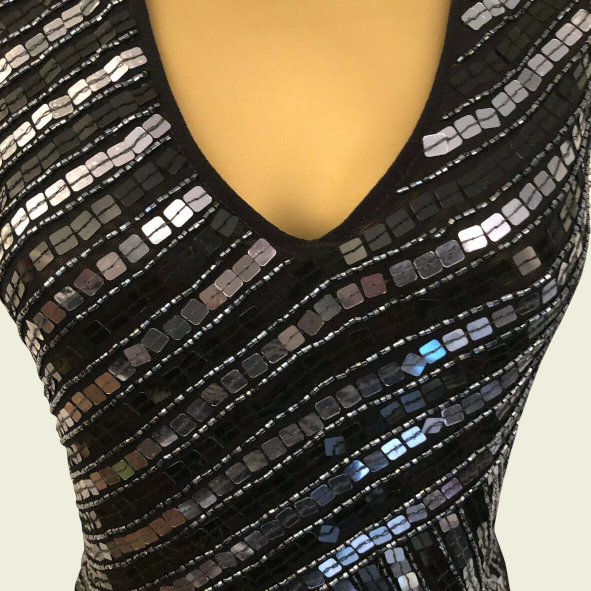 Black sequin top with a deep neckline on a mannequin against a beige background