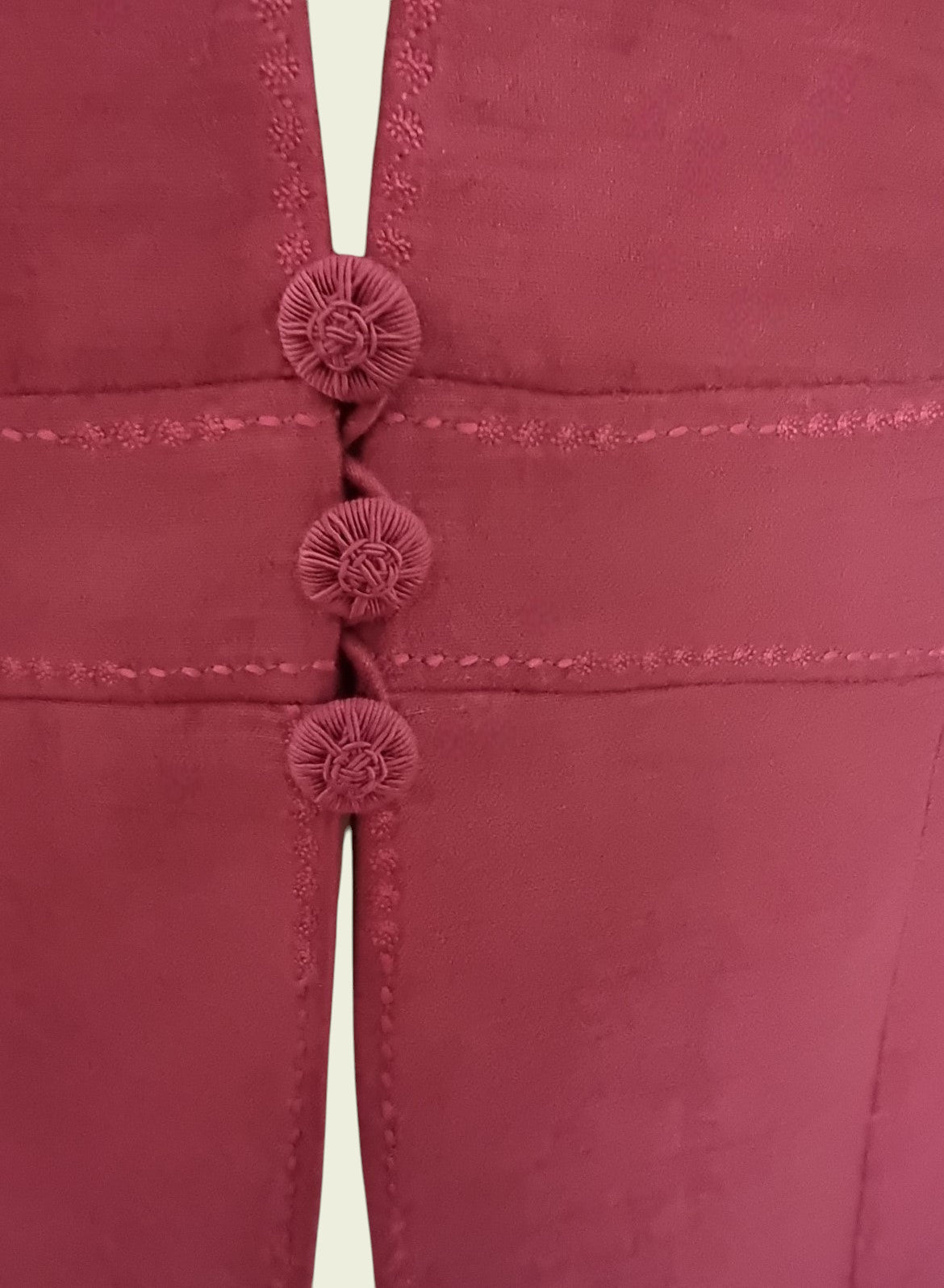 Close-up of a pink garment with button details on a light background