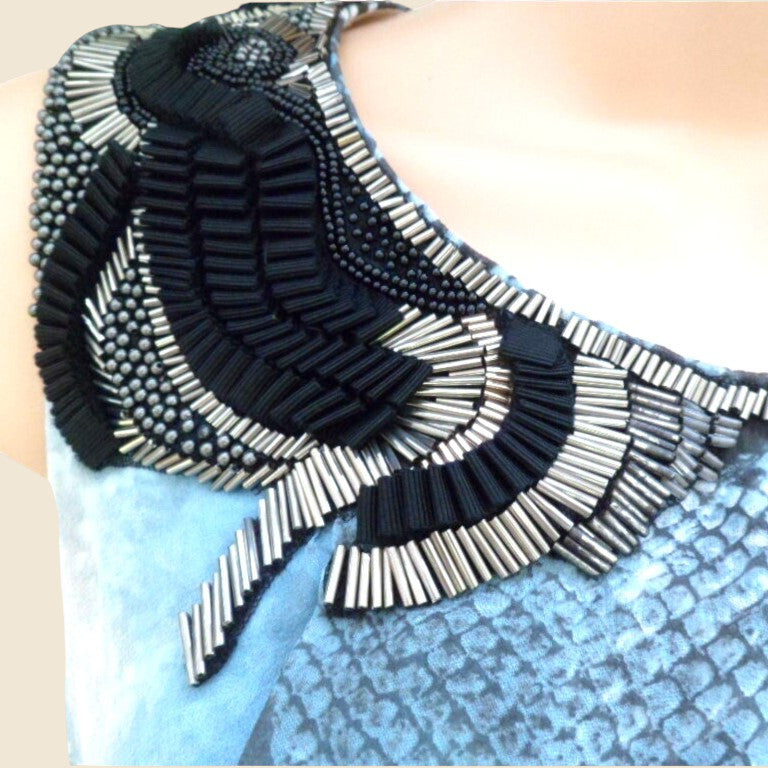 Close-up of a black and white beaded garment on a blue textured background